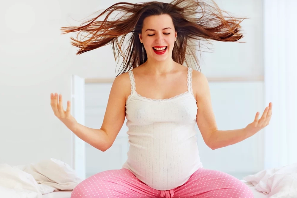 Mulher grávida com os cabelos ao vento, ilustrando mudanças causadas por hormônios durante a gravidez.